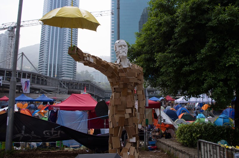 wooden Statue holding yellow umbrella